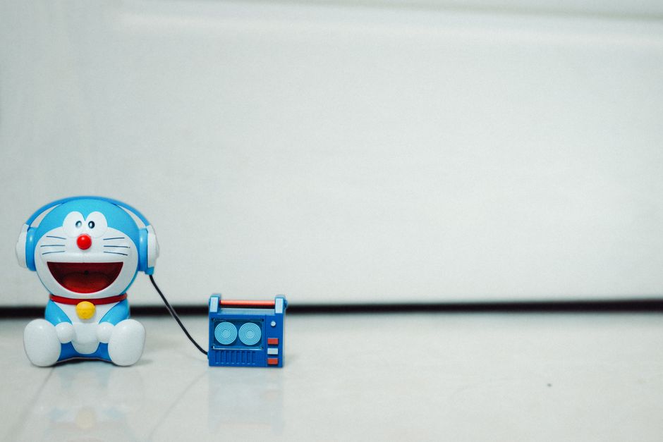 A cute blue cartoon toy listening to music with headphones. Perfect for children's themes.